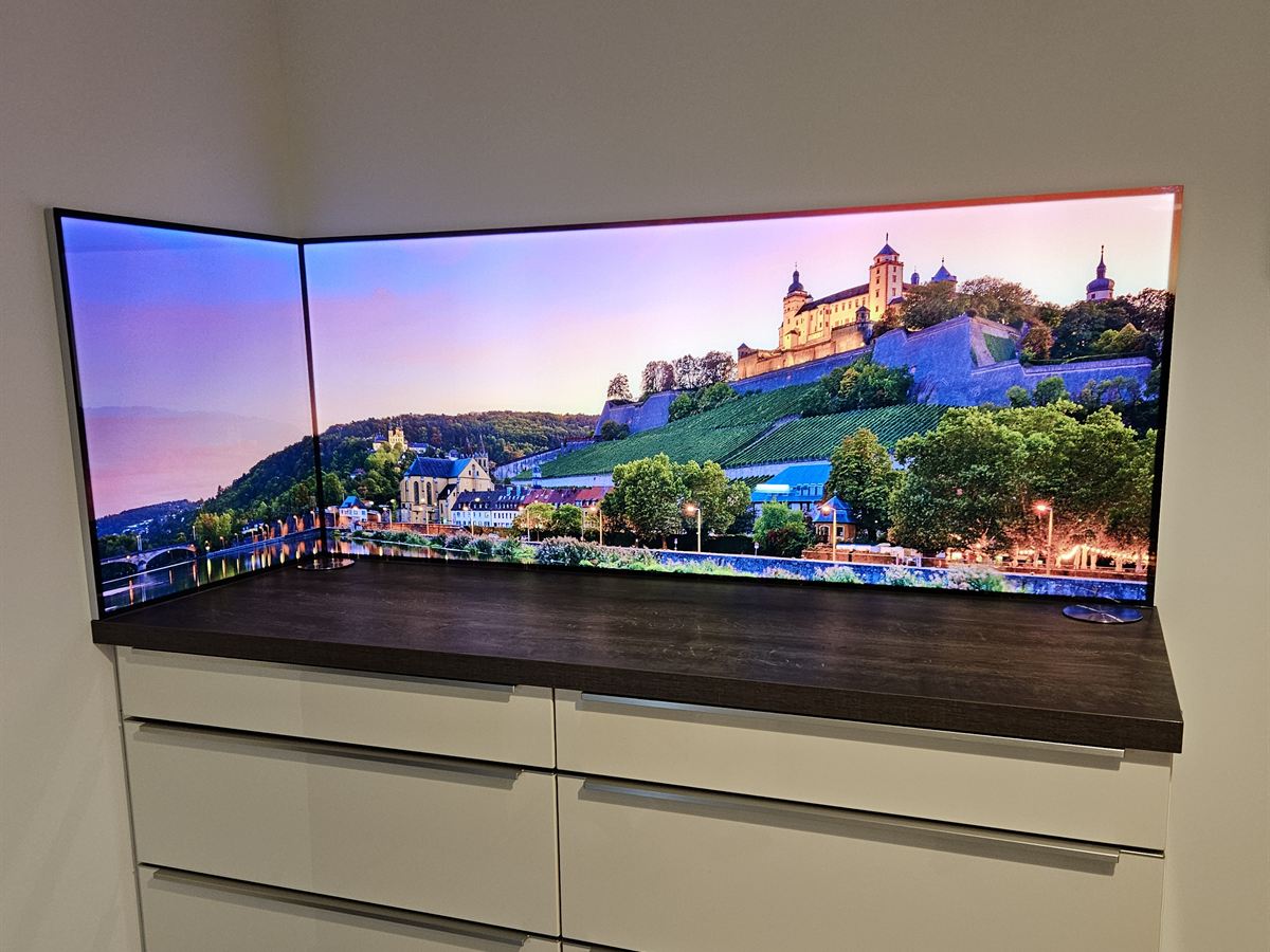 Beleuchtete LED-Glasrückwand über Eck mit Stadtmotiv über einer dunklen Arbeitsplatte
